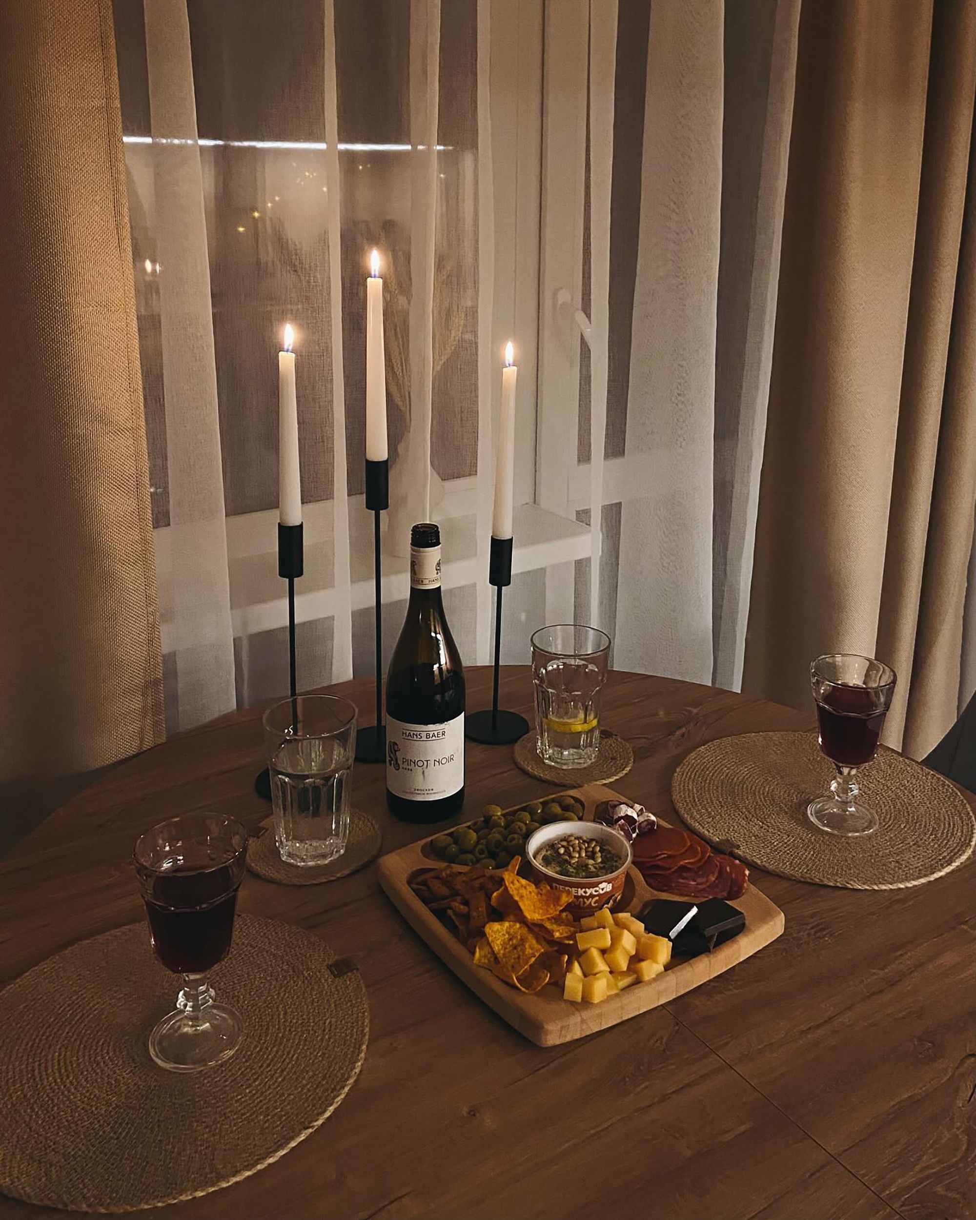 Stemningsfullt bord med levende lys, vin og småretter